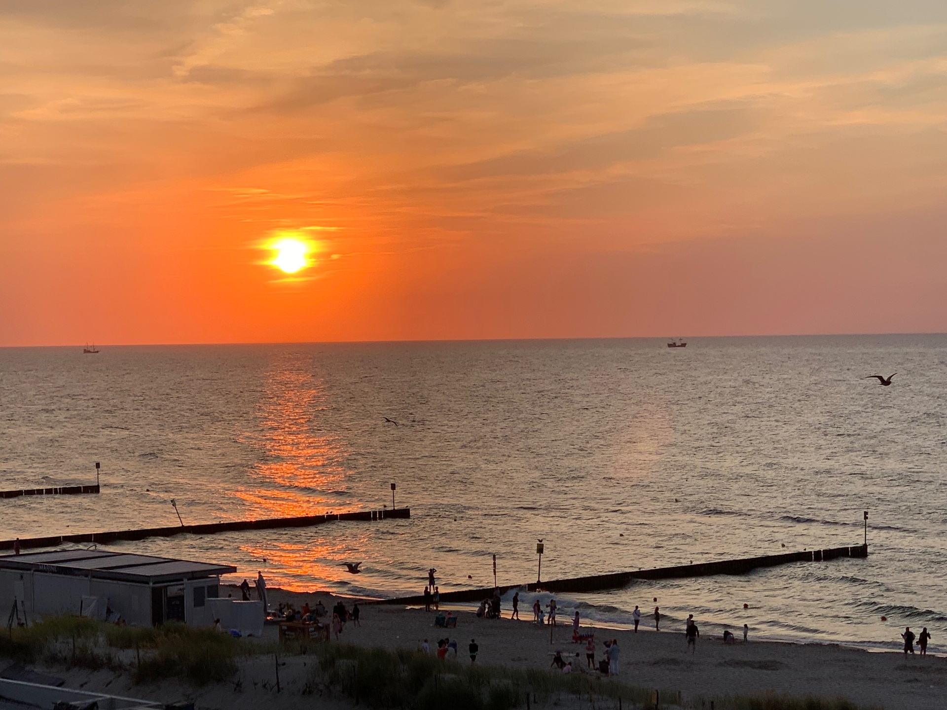 Golden sunset from the beach promenade - silhouettes of beachgoers enjoying the warm evening by the sea