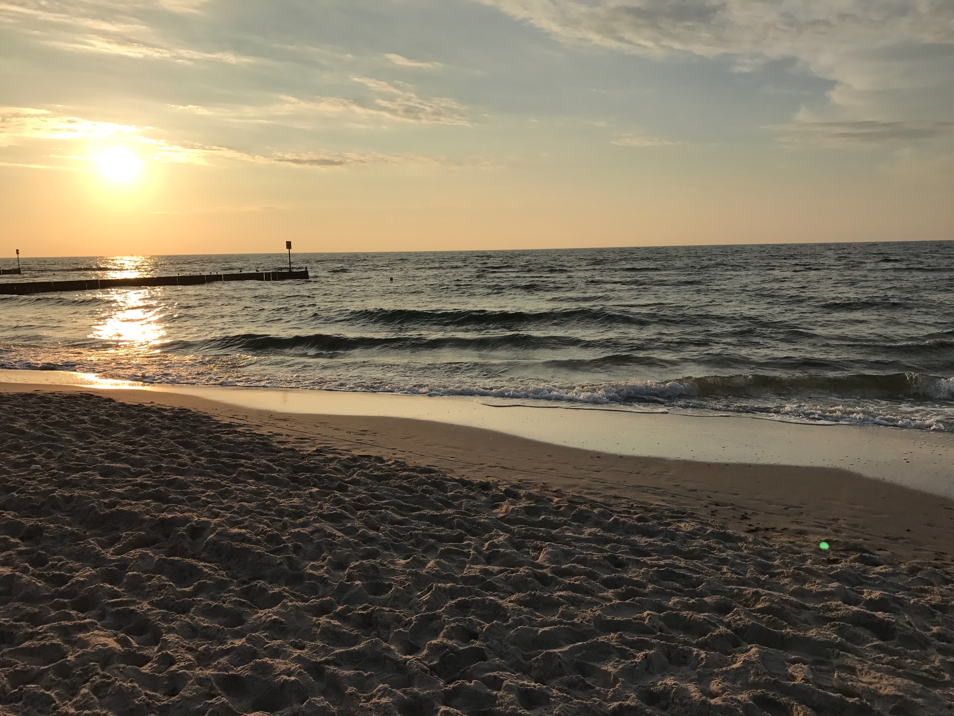 Golden hour at the Baltic - sun glistening on gentle waves with wooden groynes stretching into the sea