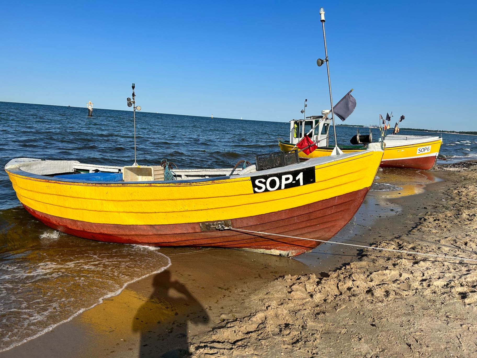 Colorful traditional fishing boats on the Sopot shore - the iconic yellow and red wooden boats against the blue Baltic