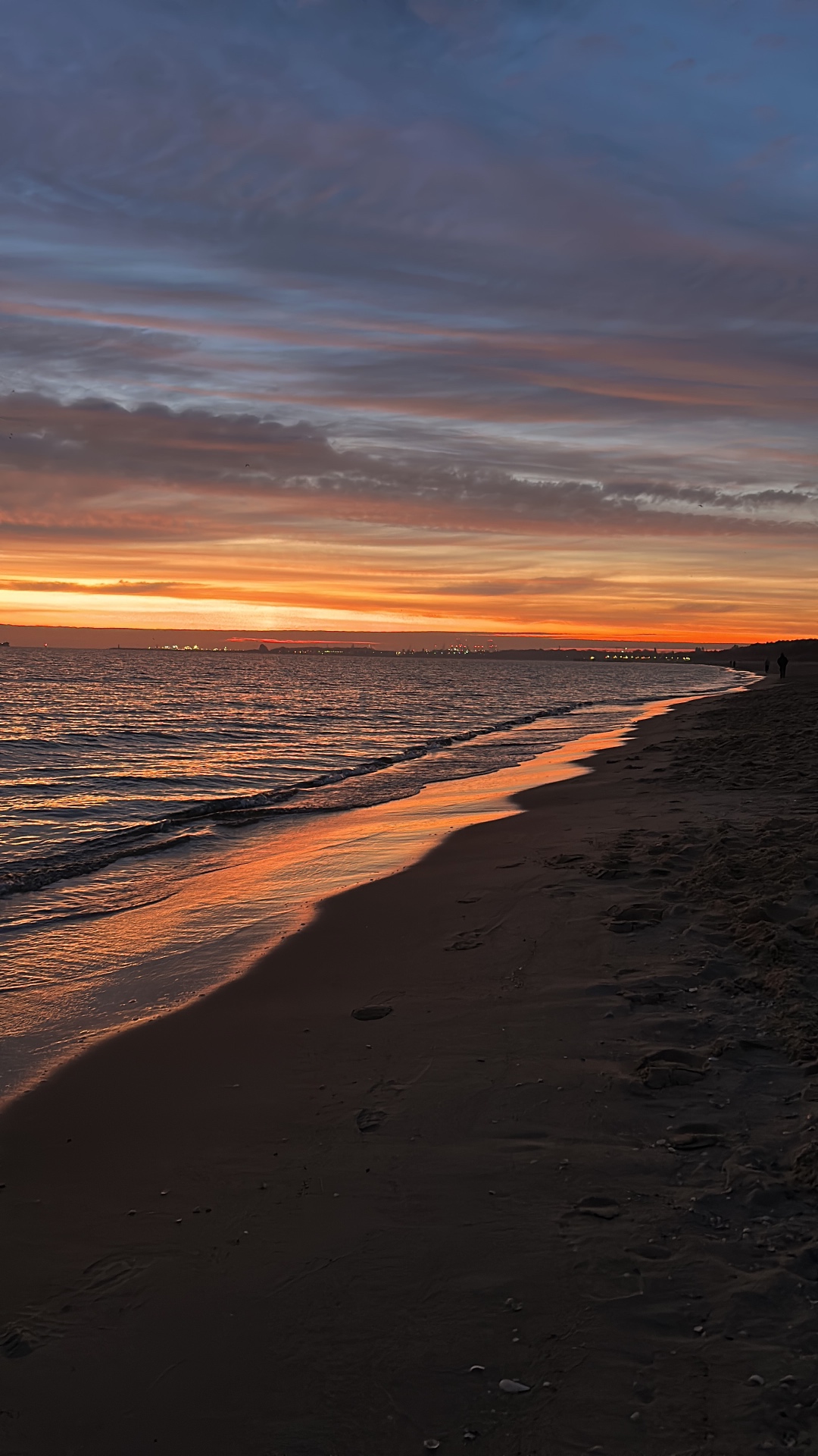 Spectacular sunset over the Baltic shoreline - vibrant orange and purple sky reflected on the wet sand