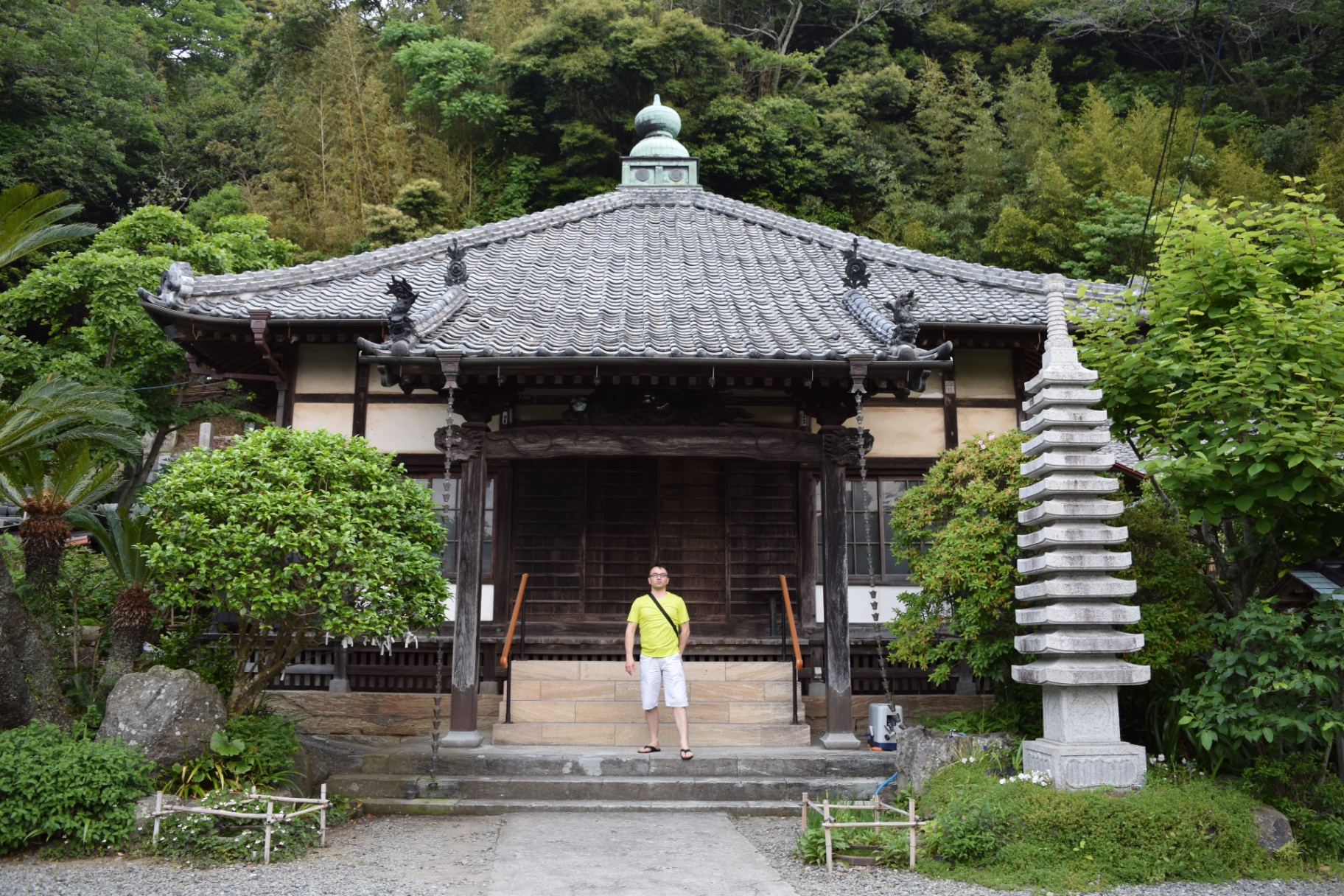 A serene Buddhist temple nestled in lush greenery - traditional gray-tiled roof and stone pagoda lantern