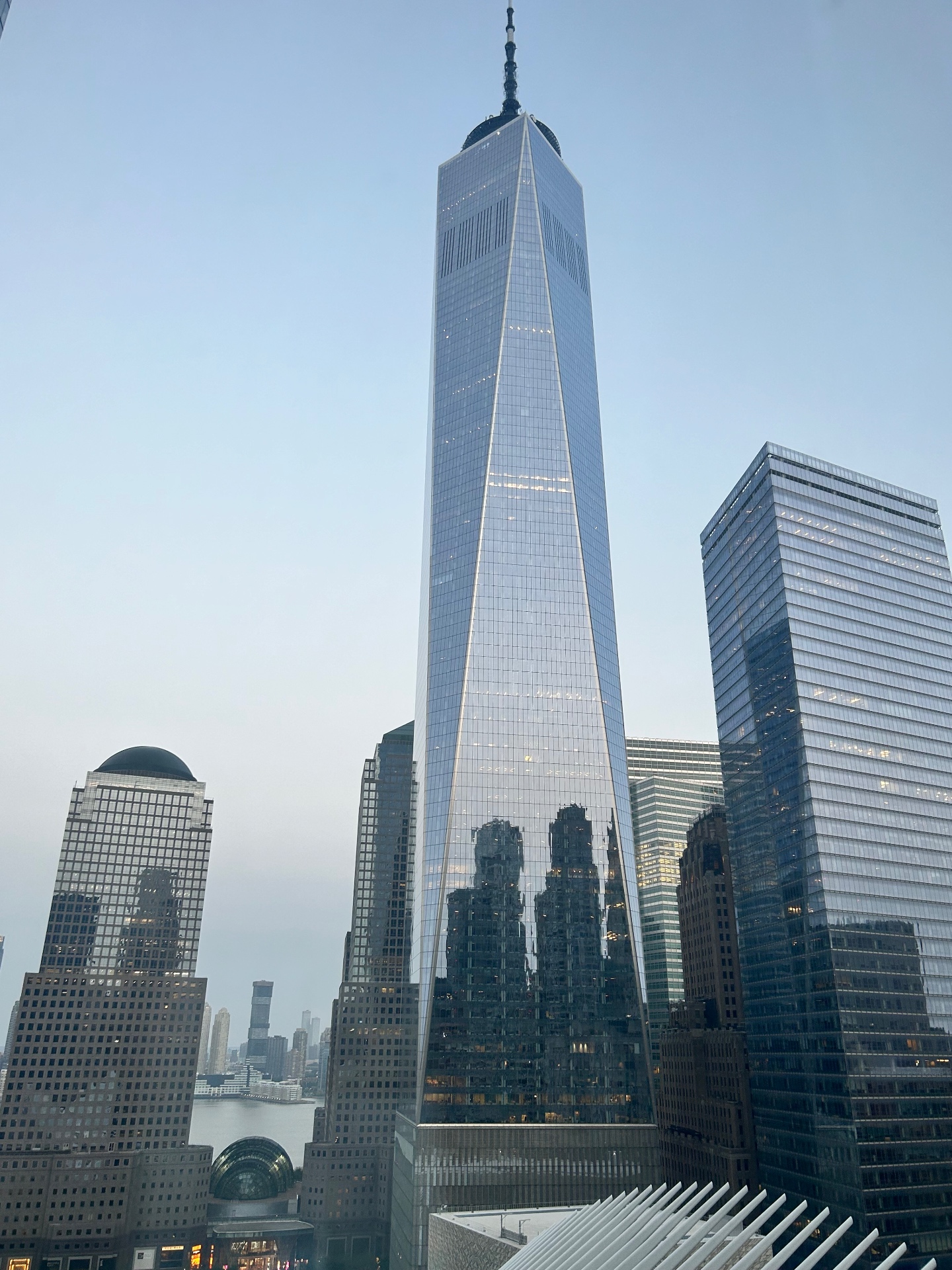 One World Trade Center towering over the Financial District - reflections of the city skyline on the glass facade at dusk