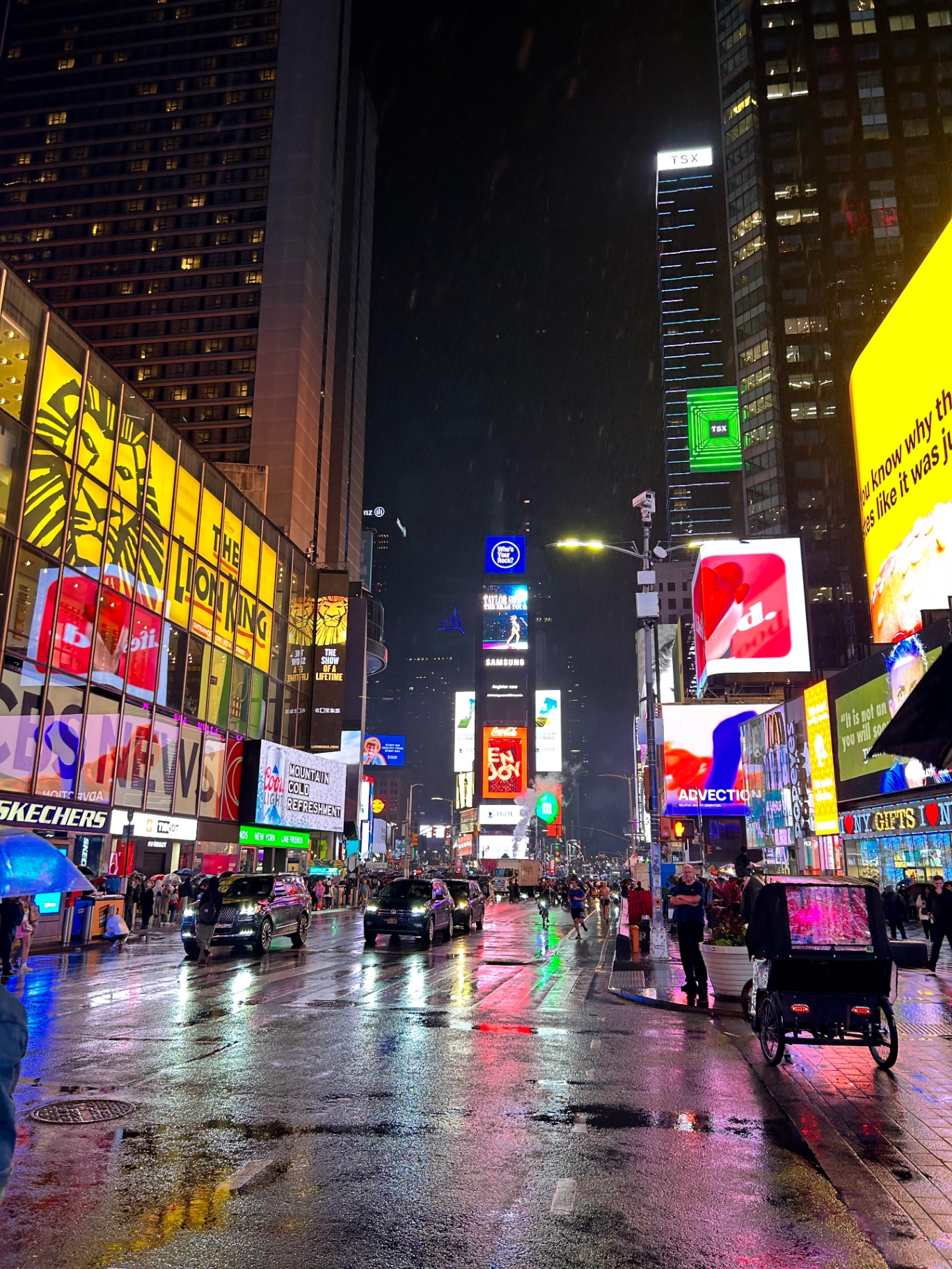 Times Square on a rainy night - neon lights reflecting on wet pavement create a magical atmosphere