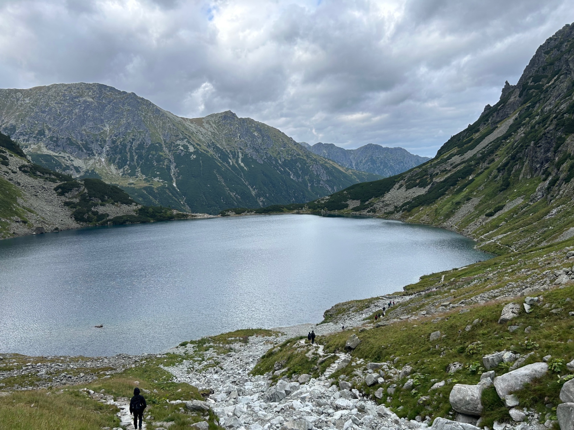 Czarny Staw pod Rysami - the black lake nestled in a stunning mountain cirque with hikers on the trail