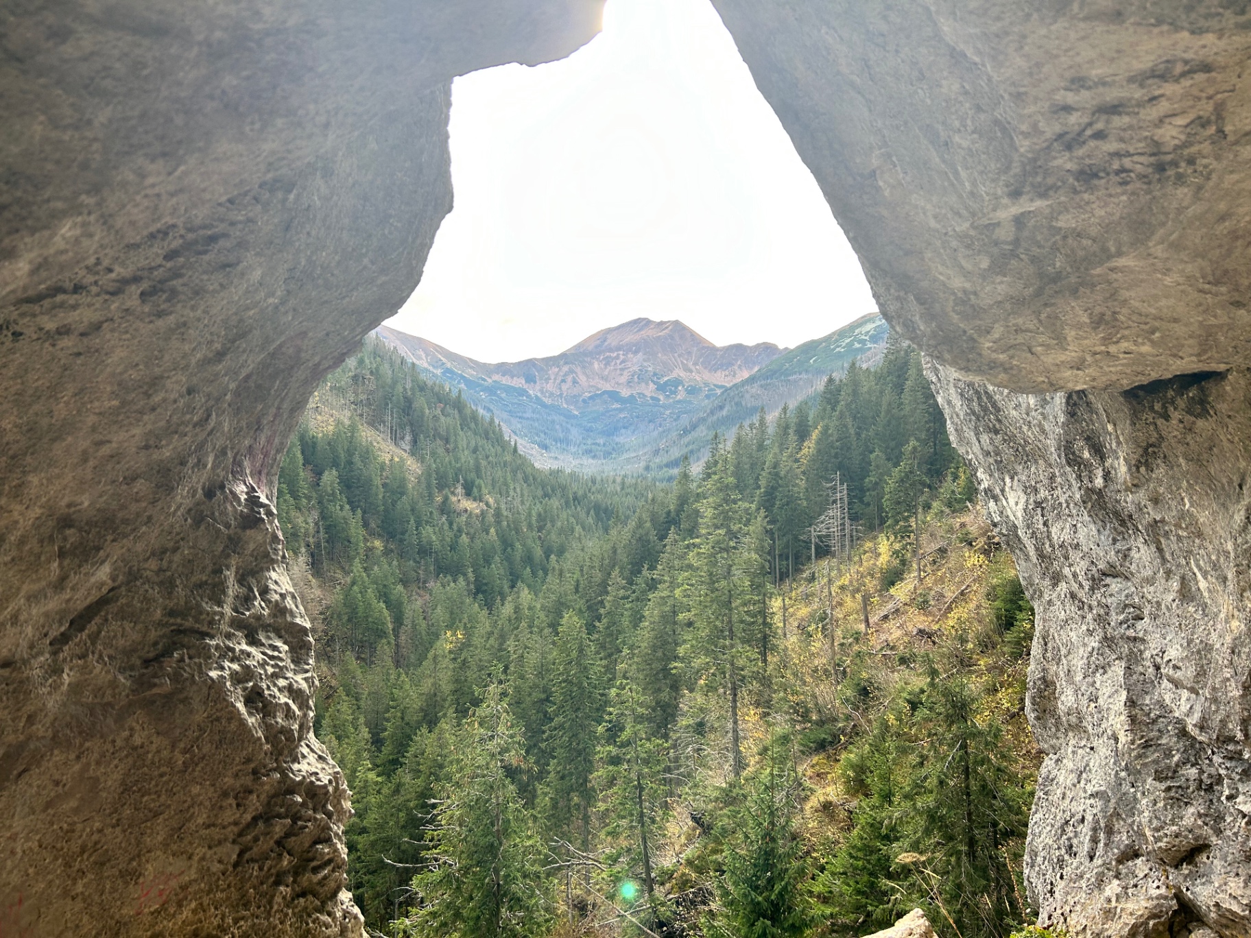 Natural rock window framing the mountain panorama - a unique perspective through ancient granite formations