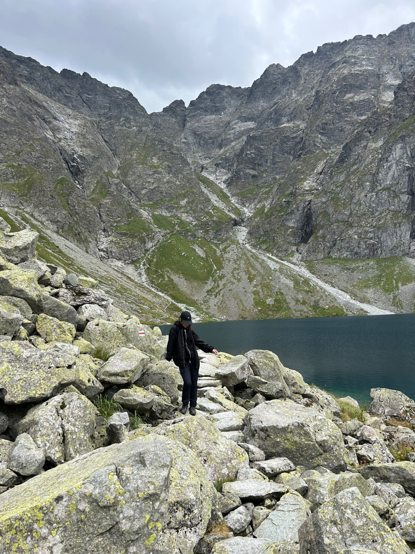 Walking on the rocky shore of Czarny Staw - surrounded by towering granite walls and pristine mountain waters